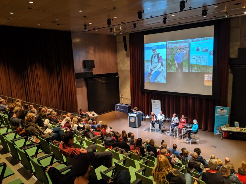 crowd listens to panel of speakers from We Are Puget Sound book launch in the Seattle Public Library auditorium