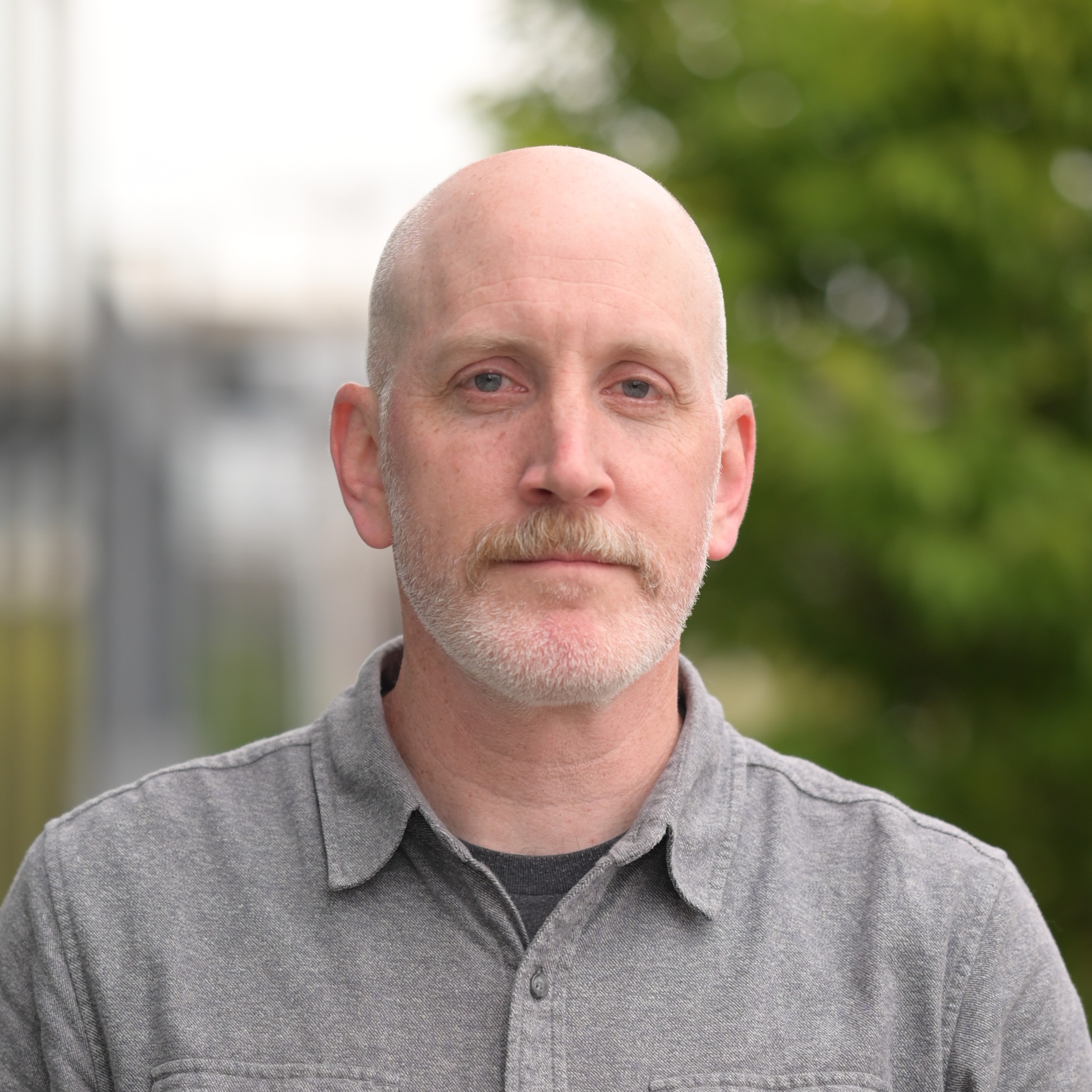 A man wears a collared shirt and looks at the camera.